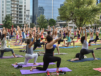 Park full of people doing yoga together