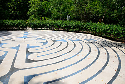 An intricate paving pattern defines a large circular space surrounded by greenery