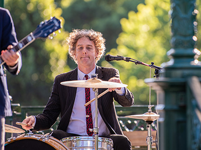 Drummer plays with his musical group outdoors in the park