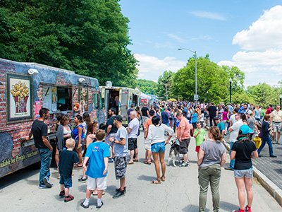 Large crowd congregating around a line of food trucks