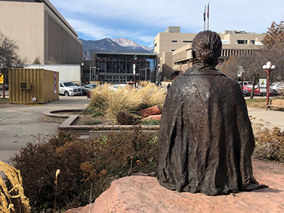 A bronze sculpture of Katharine Lee Bates sits on a rock near the Courthouse