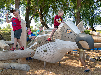 Children climbing on a large wooden bird at the playground
