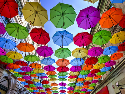 Example of a walkway covered in a playful canopy of brightly colored umbrellas suspended high above
