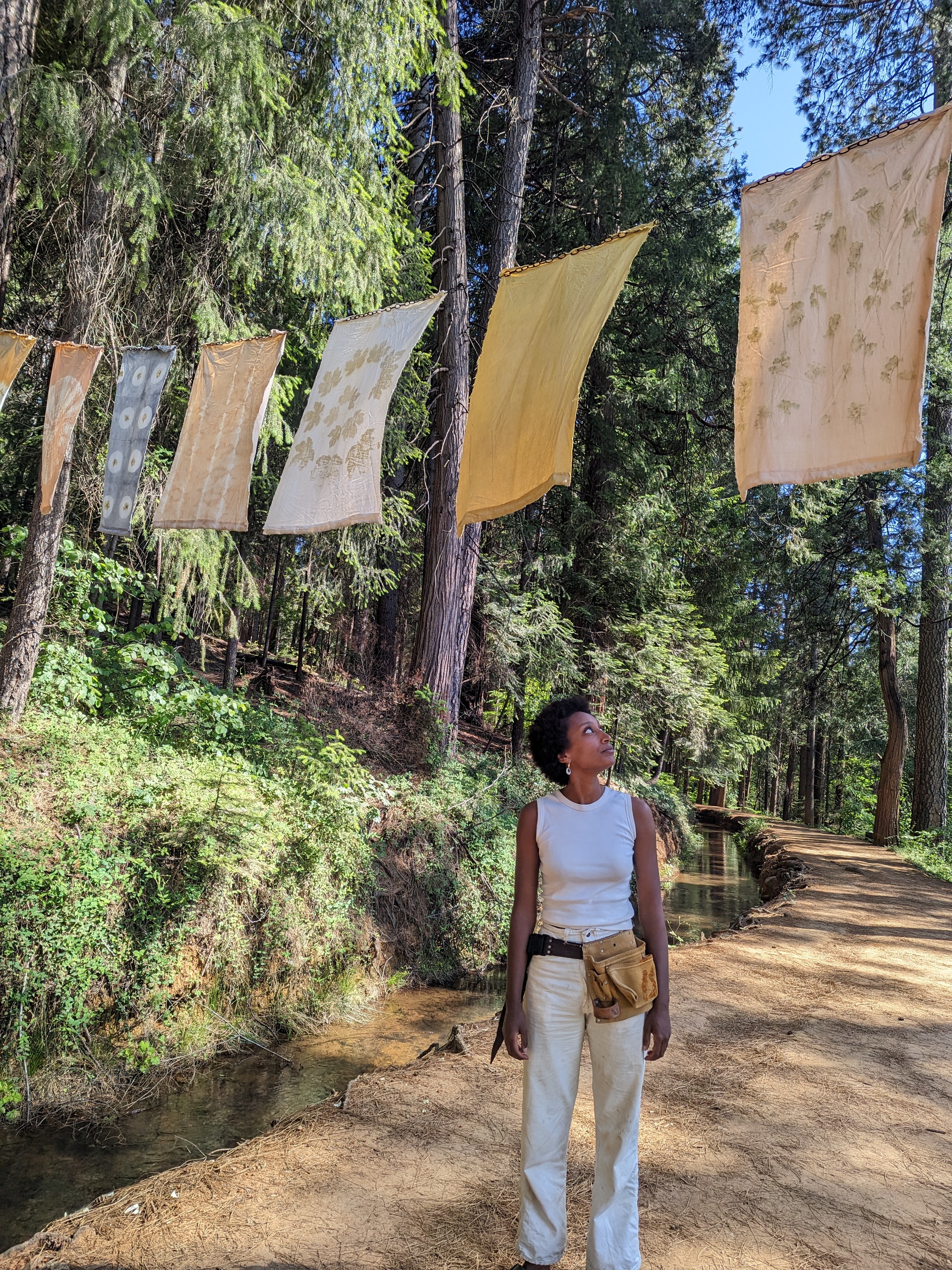 Woman walking through flags strung between trees.