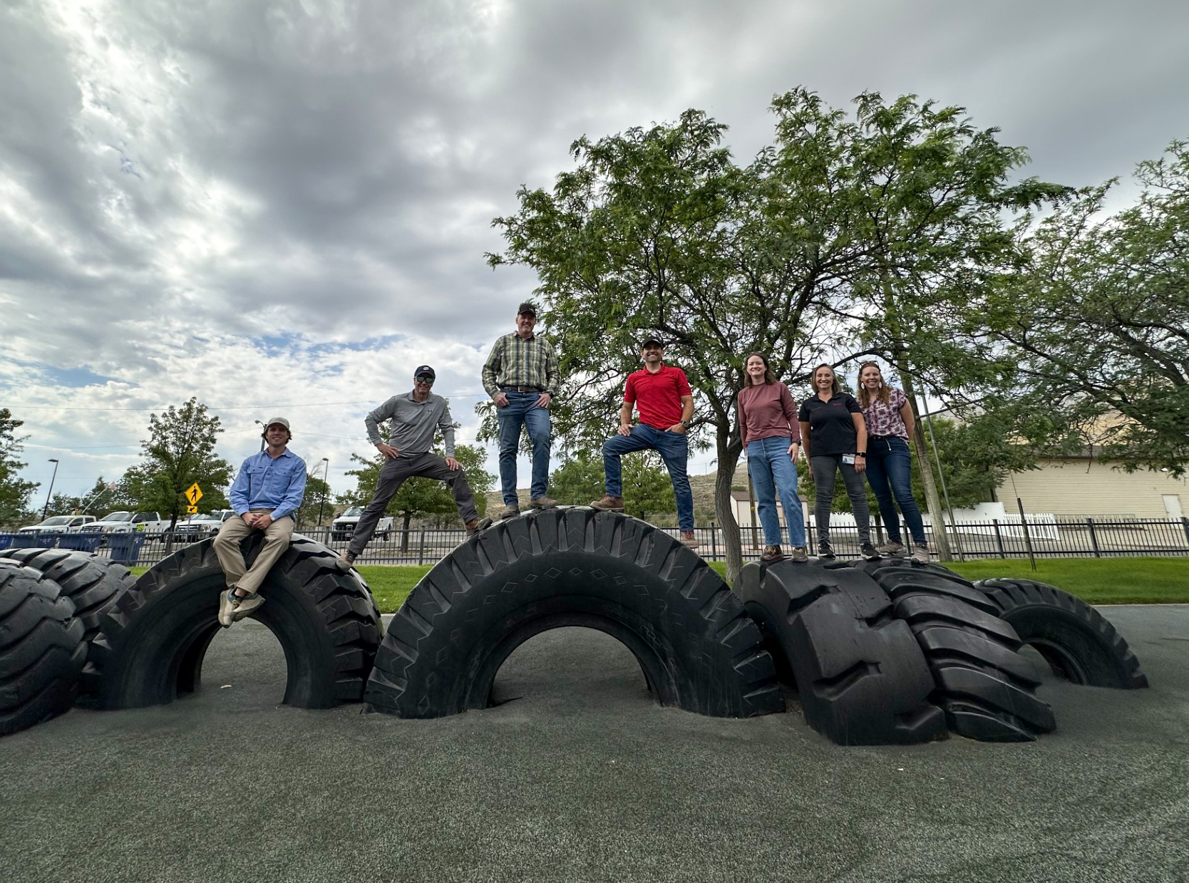 Shannon Ellsworth and other team members standing on large construction tires.